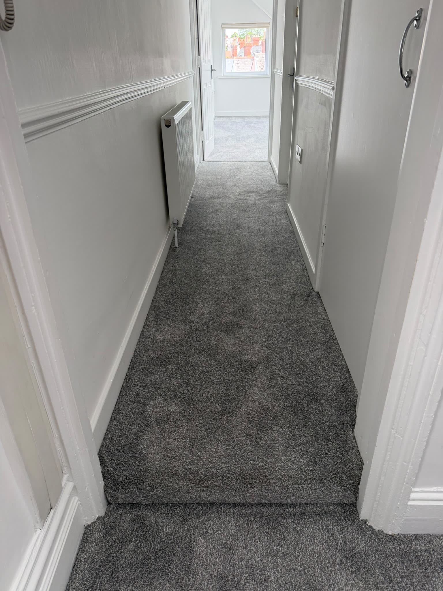New grey carpet fitted in a hallway leading to a glazed front door