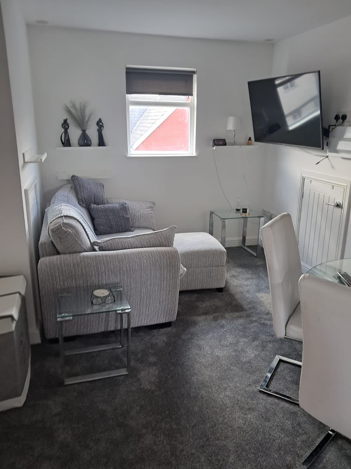 Grey carpet fitted in a lounge with a grey sofa and glass side tables