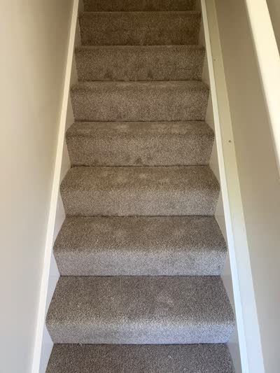 Beige carpet fitted up a staircase with white walls