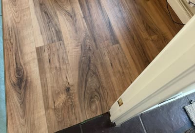 Close-up of dark oak-effect plank flooring meeting a doorway threshold