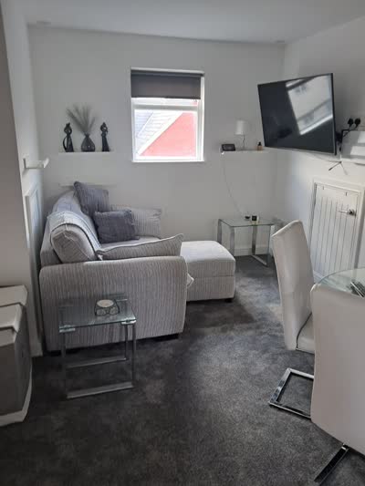 Grey carpet fitted in a lounge with a grey sofa and glass side tables