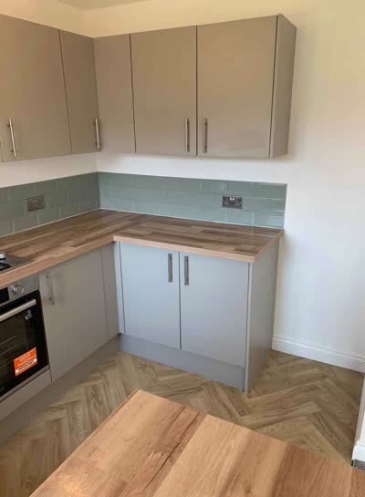 Herringbone-pattern floor in a grey kitchen with wooden worktops